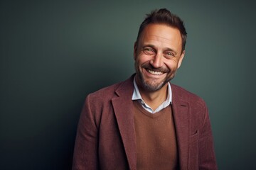 portrait of a happy Polish man in his 40s wearing a chic cardigan against an abstract background