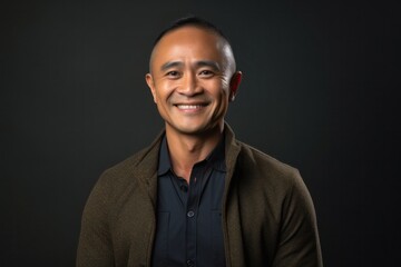 Obraz premium portrait of a happy Filipino man in his 40s wearing a chic cardigan against an abstract background