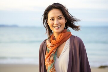 medium shot portrait of a happy Japanese woman in her 30s wearing a foulard against a beach background