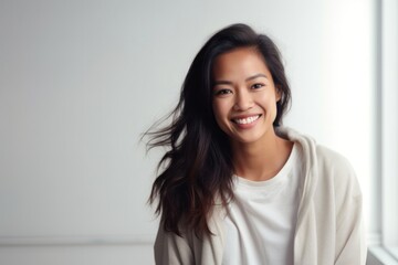 Fototapeta premium portrait of a happy Filipino woman in her 30s wearing a cozy sweater against a minimalist or empty room background