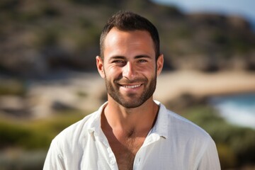 Fototapeta premium portrait of a happy Israeli man in his 30s wearing a chic cardigan against a beach background
