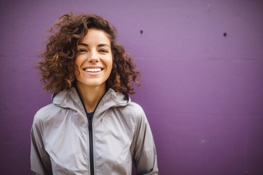 portrait of a happy Israeli woman in her 30s wearing a lightweight windbreaker against an abstract background