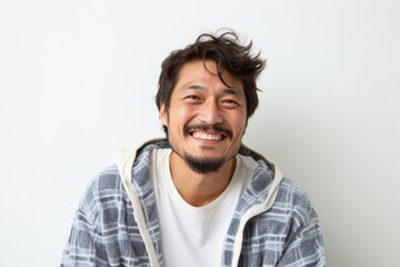 portrait of a happy Japanese man in his 30s wearing a snuggly pajama set against a white background