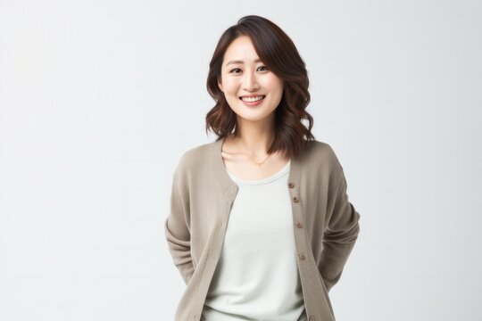 portrait of a happy Japanese woman in her 30s wearing a chic cardigan against a white background