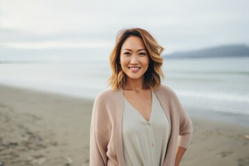 medium shot portrait of a Filipino woman in her 30s wearing a chic cardigan against a beach background
