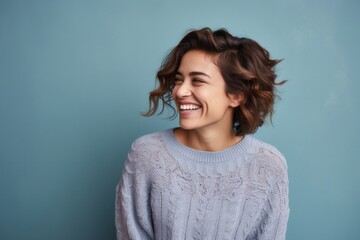portrait of a happy Mexican woman in her 30s wearing a cozy sweater against an abstract background