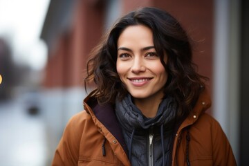 portrait of a happy Mexican woman in her 30s wearing a warm parka against an abstract background