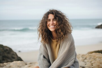 medium shot portrait of a Israeli woman in her 30s wearing a cozy sweater against a beach background