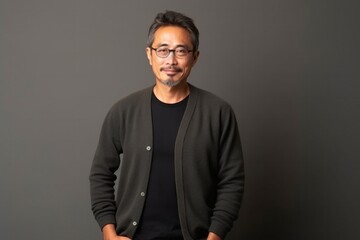 Fototapeta premium medium shot portrait of a Japanese man in his 40s wearing a chic cardigan against a minimalist or empty room background