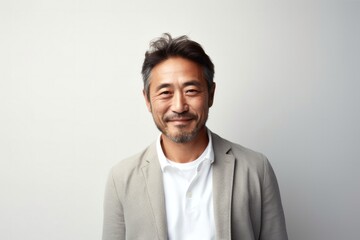 medium shot portrait of a Japanese man in his 40s wearing a chic cardigan against a minimalist or empty room background