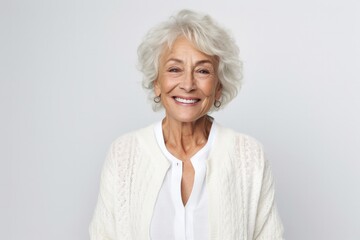 portrait of a happy Polish woman in her 70s wearing a chic cardigan against a white background