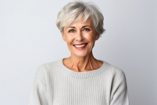 portrait of a happy Polish woman in her 60s wearing a cozy sweater against a white background