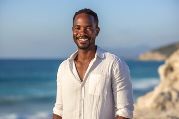 medium shot portrait of a Kenyan man in his 30s wearing a chic cardigan against a beach background