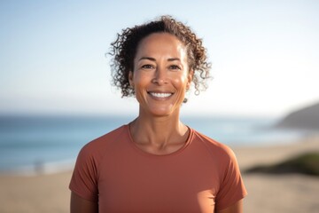 portrait of a Filipino woman in her 40s wearing a sporty polo shirt against a beach background