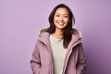 Fototapeta premium portrait of a Filipino woman in her 40s wearing a warm parka against a pastel or soft colors background