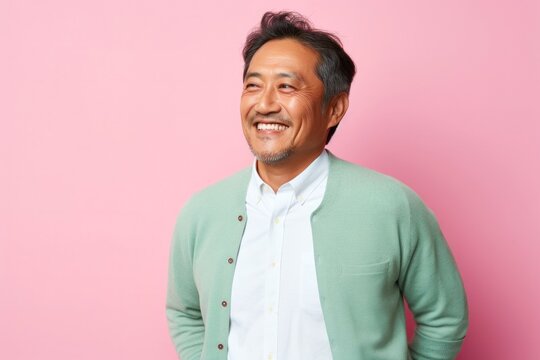 portrait of a Japanese man in his 40s wearing a chic cardigan against a pastel or soft colors background