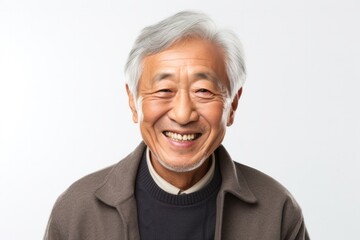 portrait of a Japanese man in his 80s wearing a chic cardigan against a white background