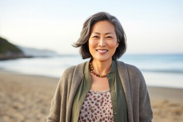 portrait of a Japanese woman in her 40s wearing a chic cardigan against a beach background