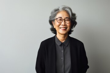 portrait of a Japanese woman in her 60s wearing a chic cardigan against a minimalist or empty room background