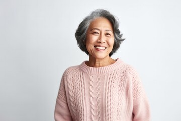medium shot portrait of a confident Filipino woman in her 60s wearing a cozy sweater against a white background