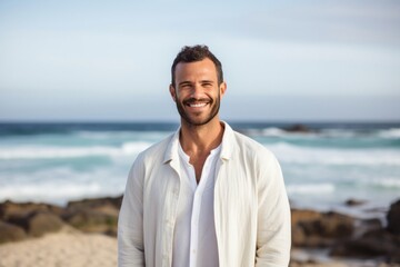 medium shot portrait of a confident Israeli man in his 30s wearing a chic cardigan against a beach background