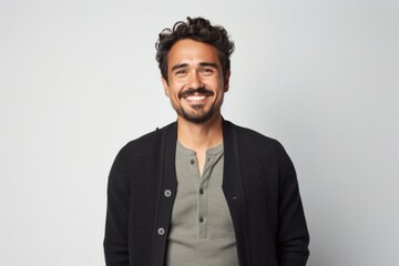 Fototapeta premium portrait of a Mexican man in his 30s wearing a chic cardigan against a white background