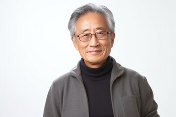 medium shot portrait of a confident Japanese man in his 60s wearing a chic cardigan against a white background