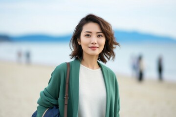 medium shot portrait of a confident Japanese woman in her 30s wearing a chic cardigan against a beach background