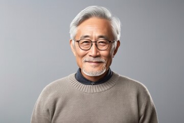 medium shot portrait of a confident Japanese man in his 80s wearing a cozy sweater against an abstract background