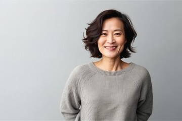 medium shot portrait of a confident Japanese woman in her 40s wearing a cozy sweater against a minimalist or empty room background