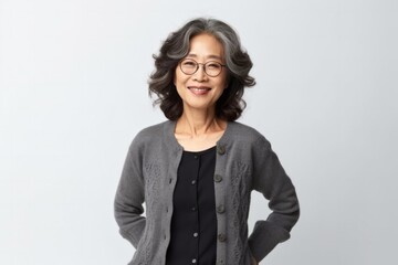 Obraz premium medium shot portrait of a confident Japanese woman in her 50s wearing a chic cardigan against a white background