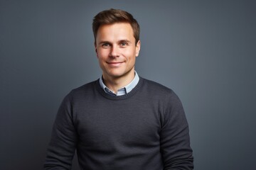 portrait of a Polish man in his 30s wearing a chic cardigan against a white background