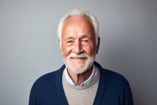 portrait of a Polish man in his 70s wearing a chic cardigan against a minimalist or empty room background