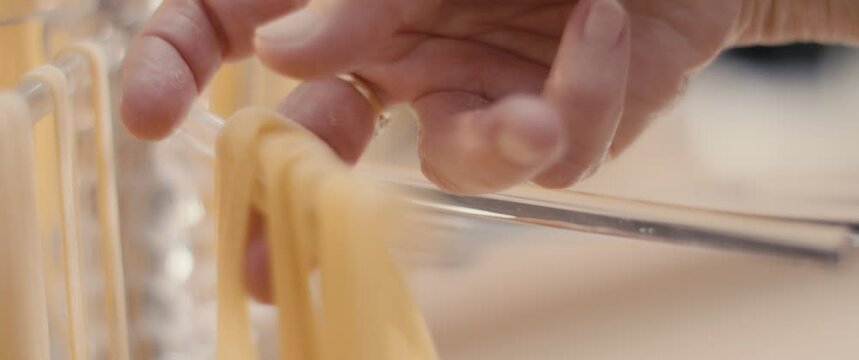 Female hand picks dried tagliatelle pasta on tool kitchen in close up