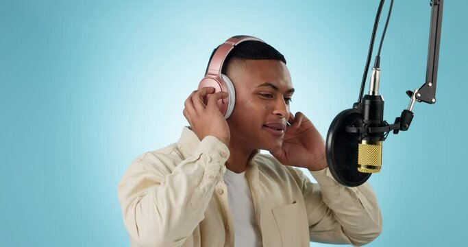 Rapper, musician and man recording music or audio isolated in a studio blue background to sing a song. Artist, hip hop and creative person with microphone for broadcast on radio, voiceover singing