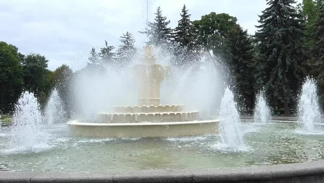 fountain in the central park of the city of Vinnitsa Ukraine rainy weather Large trees and a fountain against the background of a cloudy sky water flows. Ordinary life