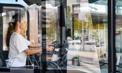 Photo of female bus driver through the glass of driver's cabin with reflections on glass. Gender equality in employment concept. © Barillo_Images