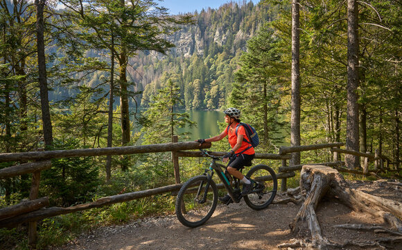nice senior woman on her electric mountain bike cycling Lake Feldsee in the  German Black Forest near Titisee-Neustadt, Baden-W&uuml;rttemberg, Germany