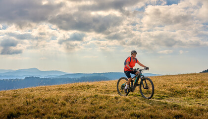 Fototapeta na wymiar nice senior woman on her electric mountain bike cycling on Feldberg summit, top of German Black forest