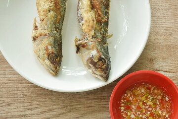 crispy fried fresh mackerel fish arranging on plate dipping spicy chili sauce in cup  