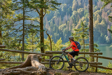 nice senior woman on her electric mountain bike cycling Lake Feldsee in the  German Black Forest...