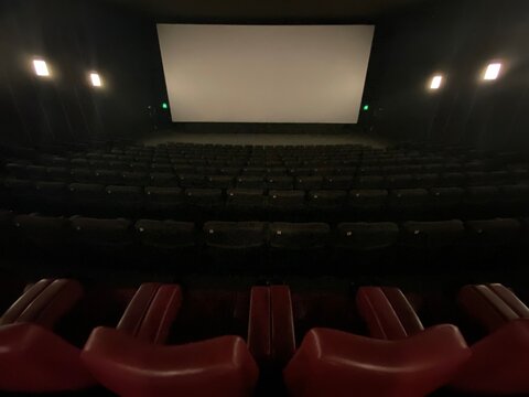 Inside A Modern Cinema, No People Are Visible And The Screen Is Off.