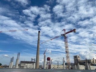Construction site in a big city, background is a cloudy blue sky. - 649749607