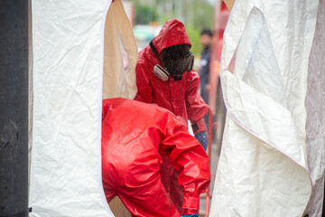 Rescuers wearing red hazmat suits assembled a Inflatable sterilization tunnel tentst. To be used in...