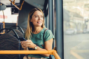 Lifestyle portrait of a young businesswoman sitting with smart phone at the modern train. Woman on...