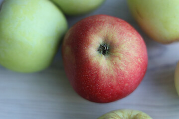 Group of beautiful local green and red apples on the white wooden table. Ripe, fresh, juicy and healthy, harvested in September in the farmer garden. Close up. Top view. Selective focus.