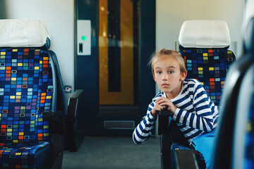 Cute boy sitting in commuter electric train. Little kid traveling on the train.
