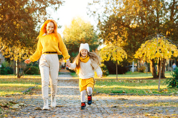 Lovely girl with her mom having fun on the walk. Autumn holidays, lifestyle.