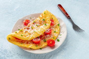 An omelet with tomato and parsley, eggs for breakfast, a healthy vegetarian dish with cheese, with a fork - obrazy, fototapety, plakaty