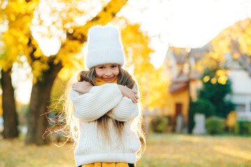 Happy girl walking in autumn park. Little girl wearing warm knitted sweater.